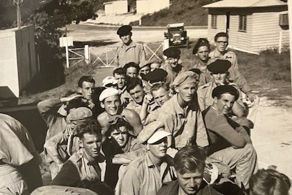 An old photo of a group of about 30 men on the back of an RAAF truck. 