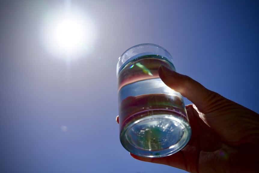 Glass of water being held up to the sunlight.