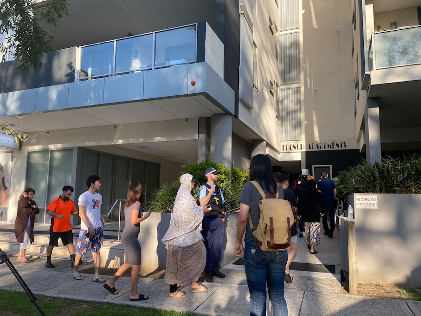 People line up outside an apartment complex.