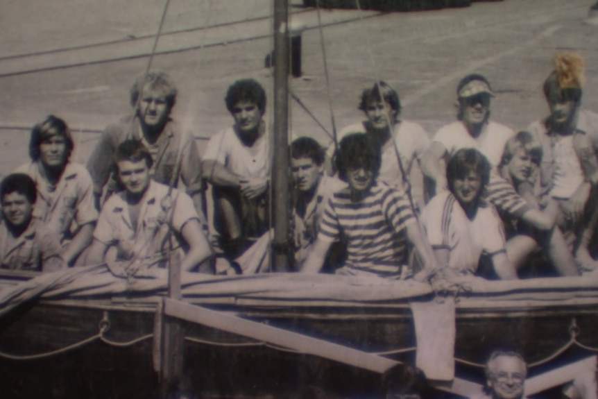 Black and white historical image of boat builders sitting on a ship