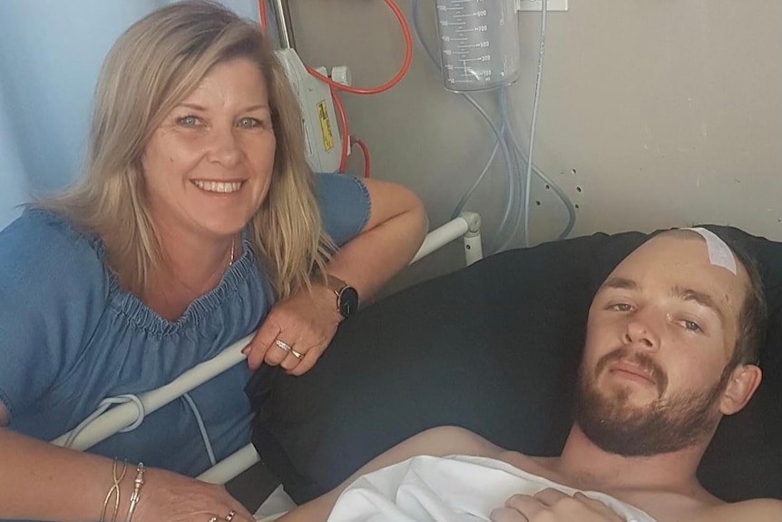 A woman sits with her son next to his hospital bed. 