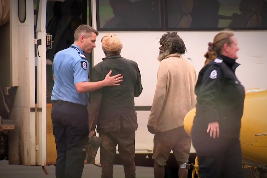 Two men being escorted to a bus