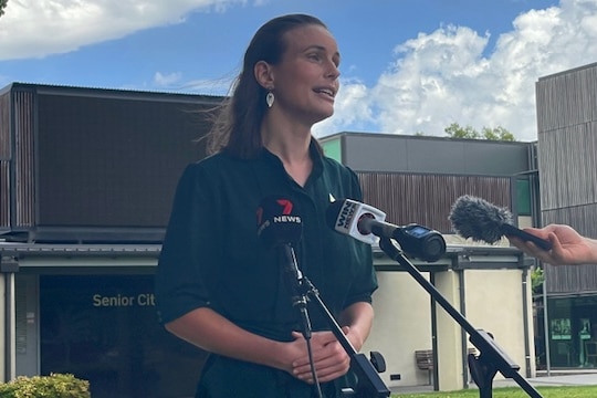 A woman with long hair speaks to the media.