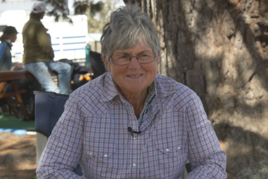 A woman in a shirt sitting in the outdoors.