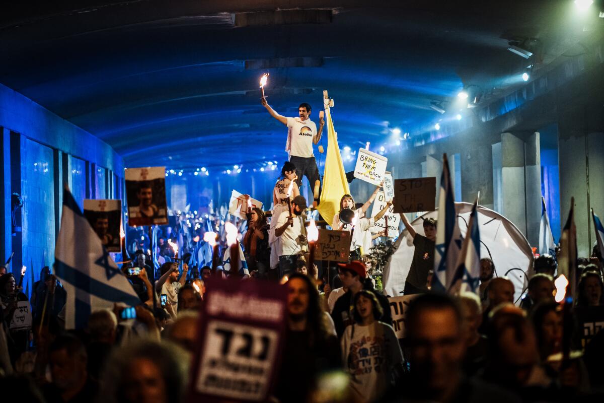 JERUSALEM, ISRAEL -- APRIL 2, 2024: Protesters holding flags, banners and lit candles march through central Jerusalem, Israel, Tuesday, April 2, 2024. Thousands of demonstrators surged through Jerusalem demanding that the government reach a cease-fire deal to free the remaining hostages held in Gaza by Hamas militants, hold early national elections and argued in favor for all draft-aged religious ultra orthodox to join the military. (MARCUS YAM / LOS ANGELES TIMES)