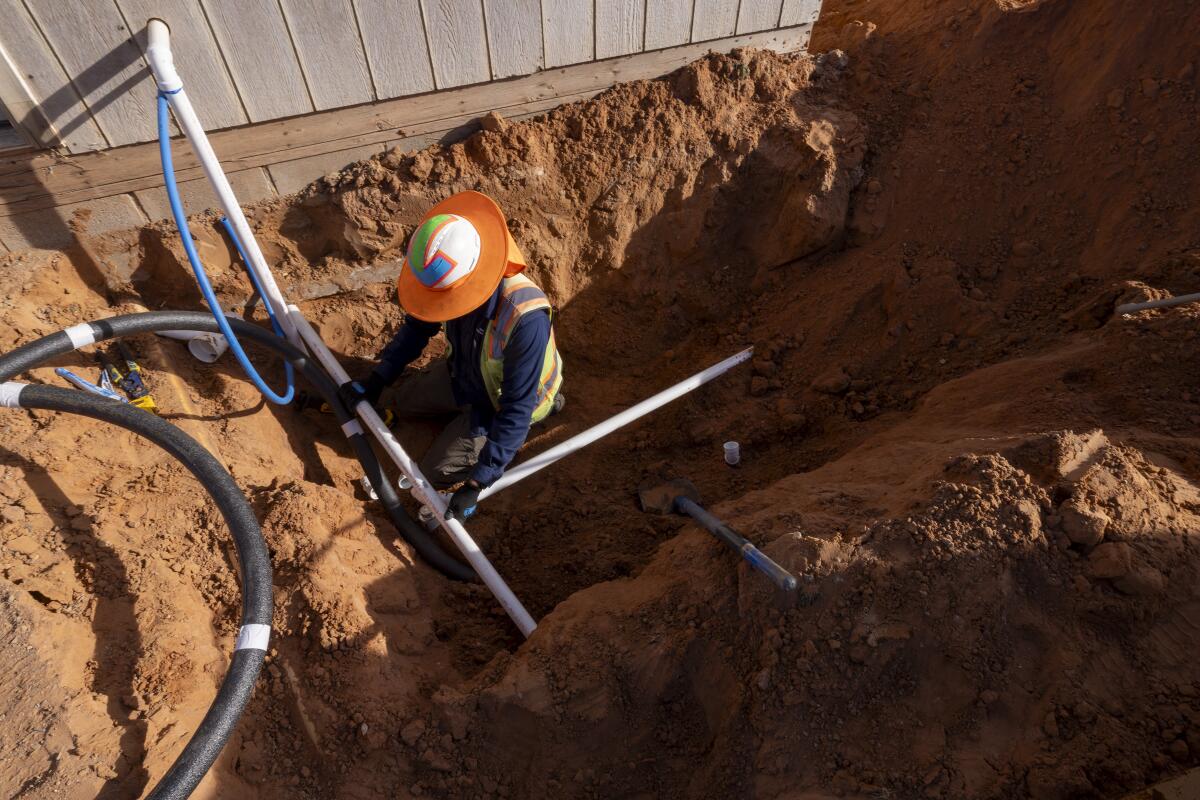 DigDeep employee Donovan Smallcanyon fits new drainage pipes in a ditch.