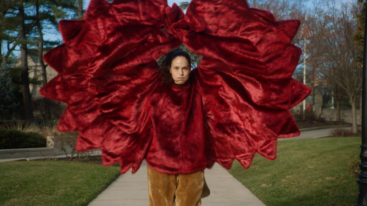 A woman poses in a mascot's uniform on a college campus.