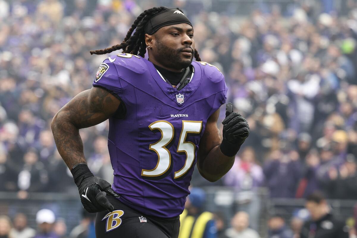 Former Baltimore Ravens running back Gus Edwards runs on a field.