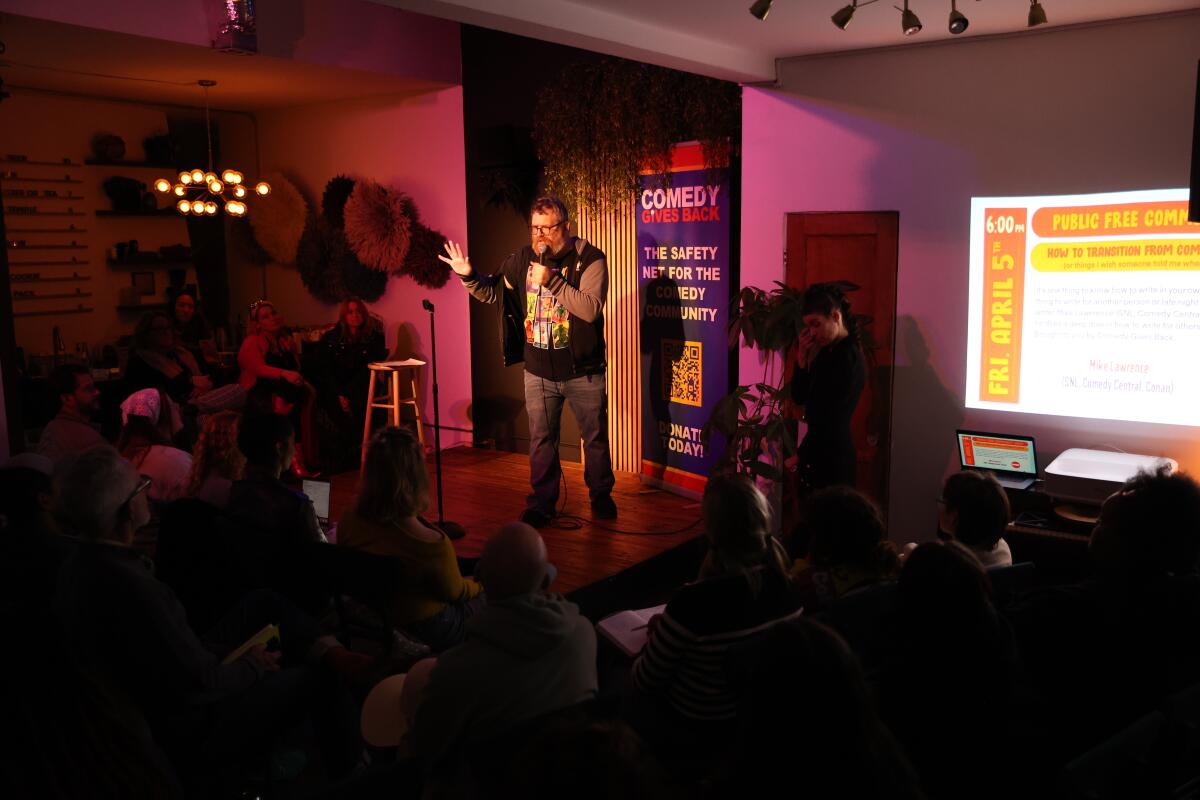 Bearded man on stage talking into a microphone