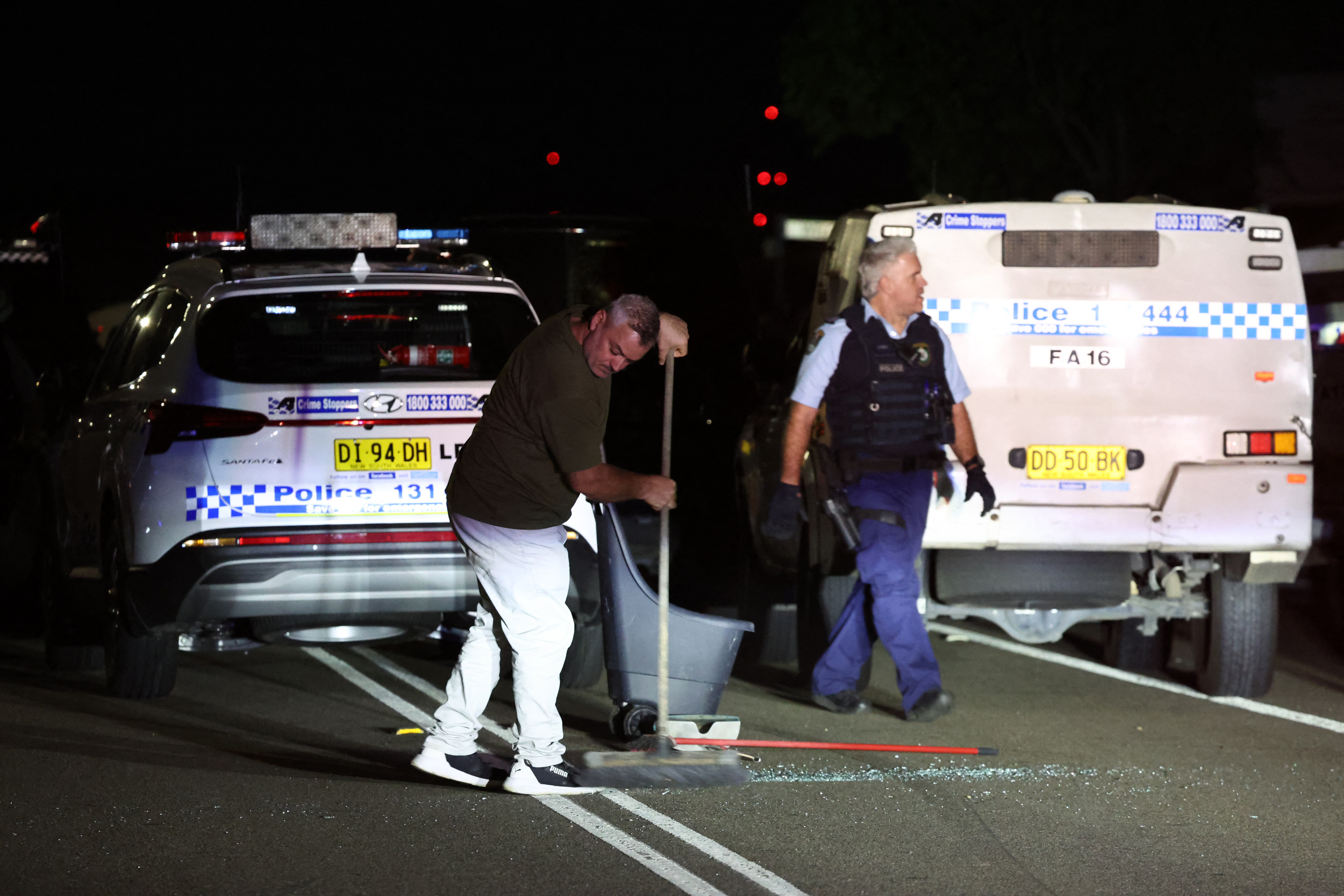 People clearing up shattered glass from broken  police vehicles