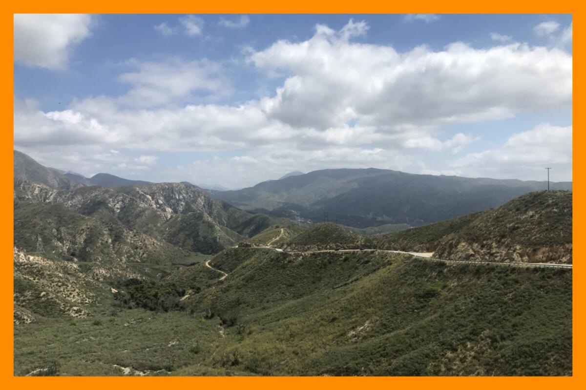 A mountain path winds around mountains in the distance