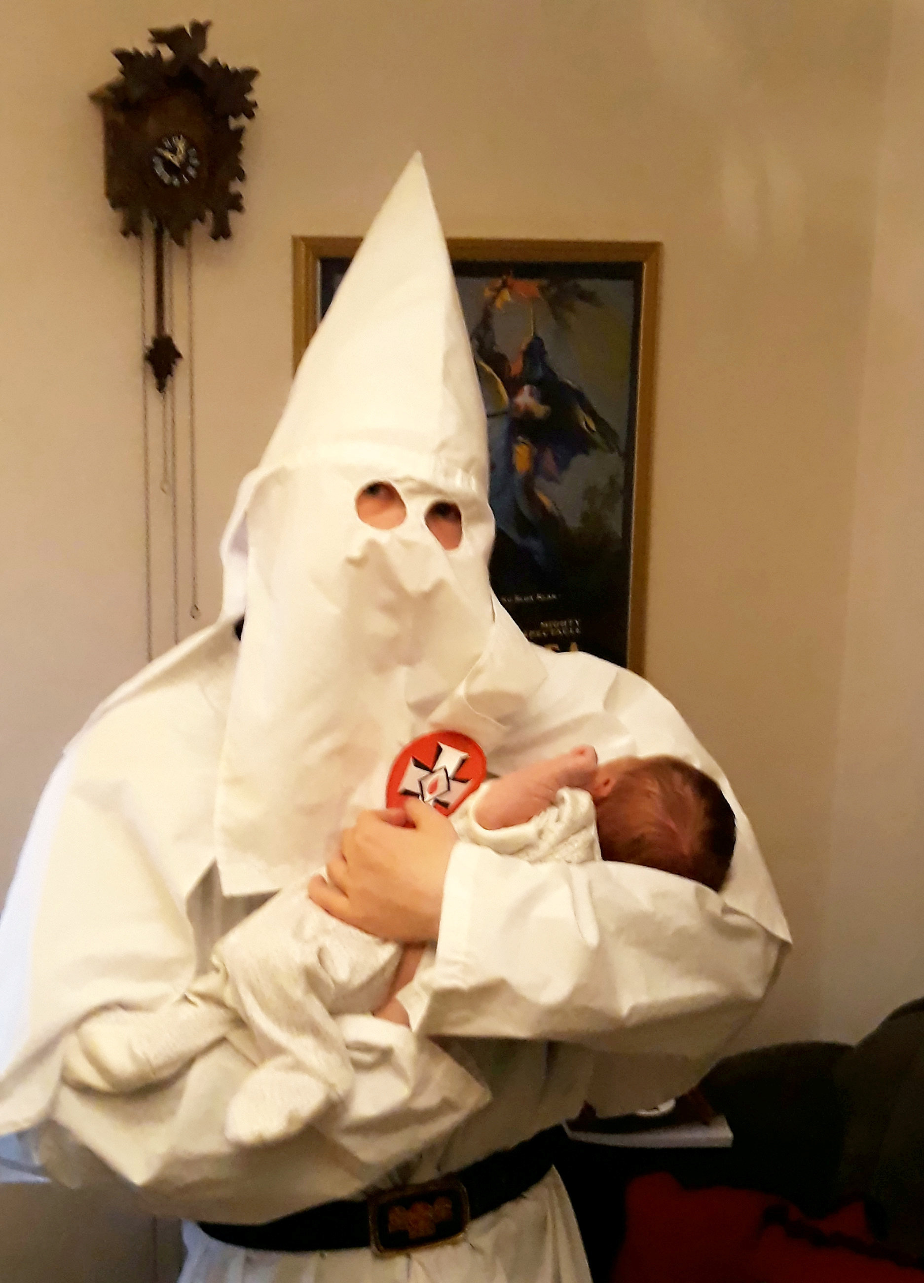 Thomas holds a baby whilst wearing a Ku Klux Klan outfit