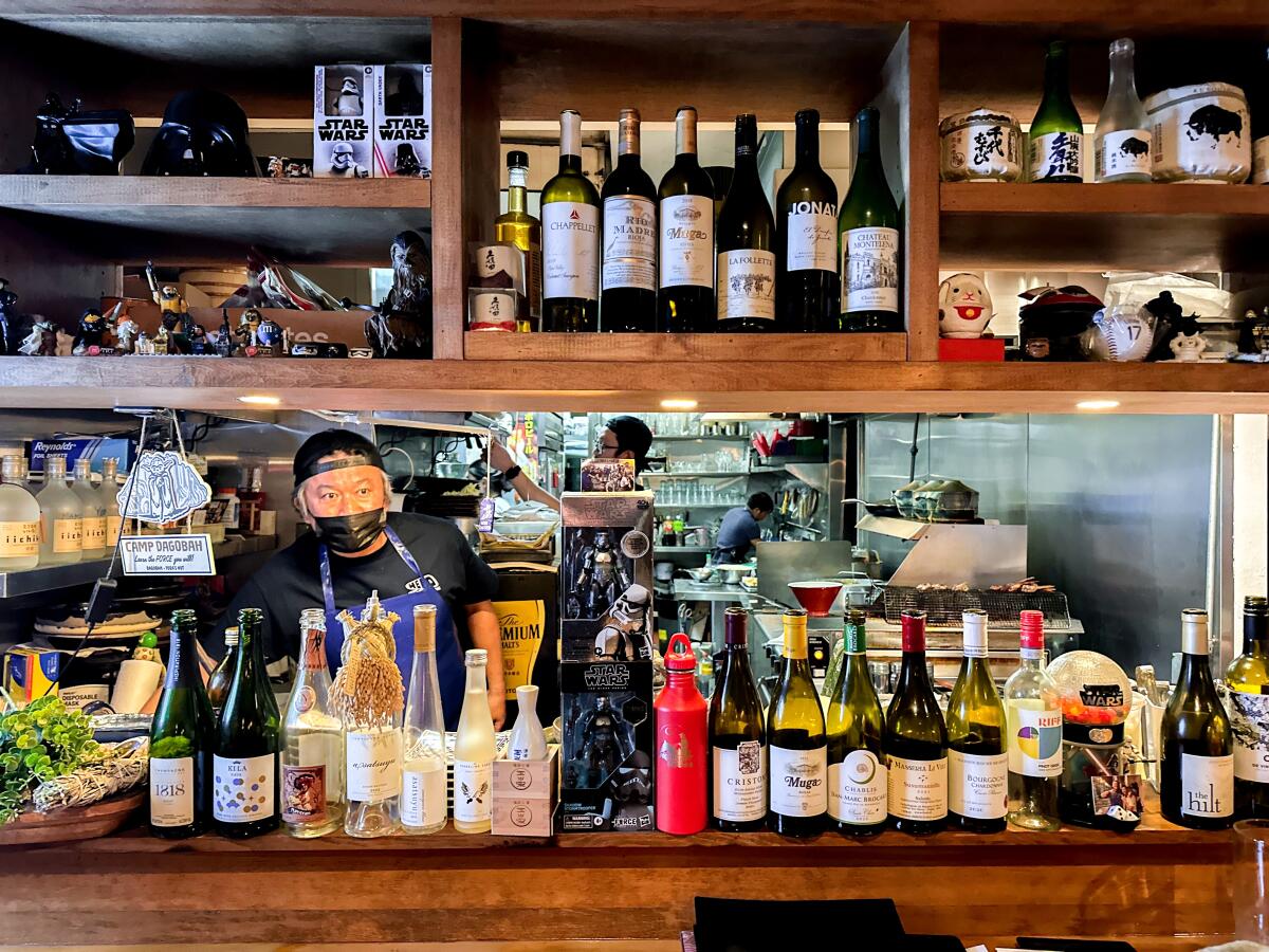 Wine and sake bottles line the kitchen window at Hiro Chiya's Hakata Izakaya Hero in Westwood