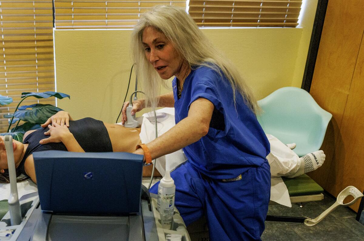 A doctor examines a woman on a bed.