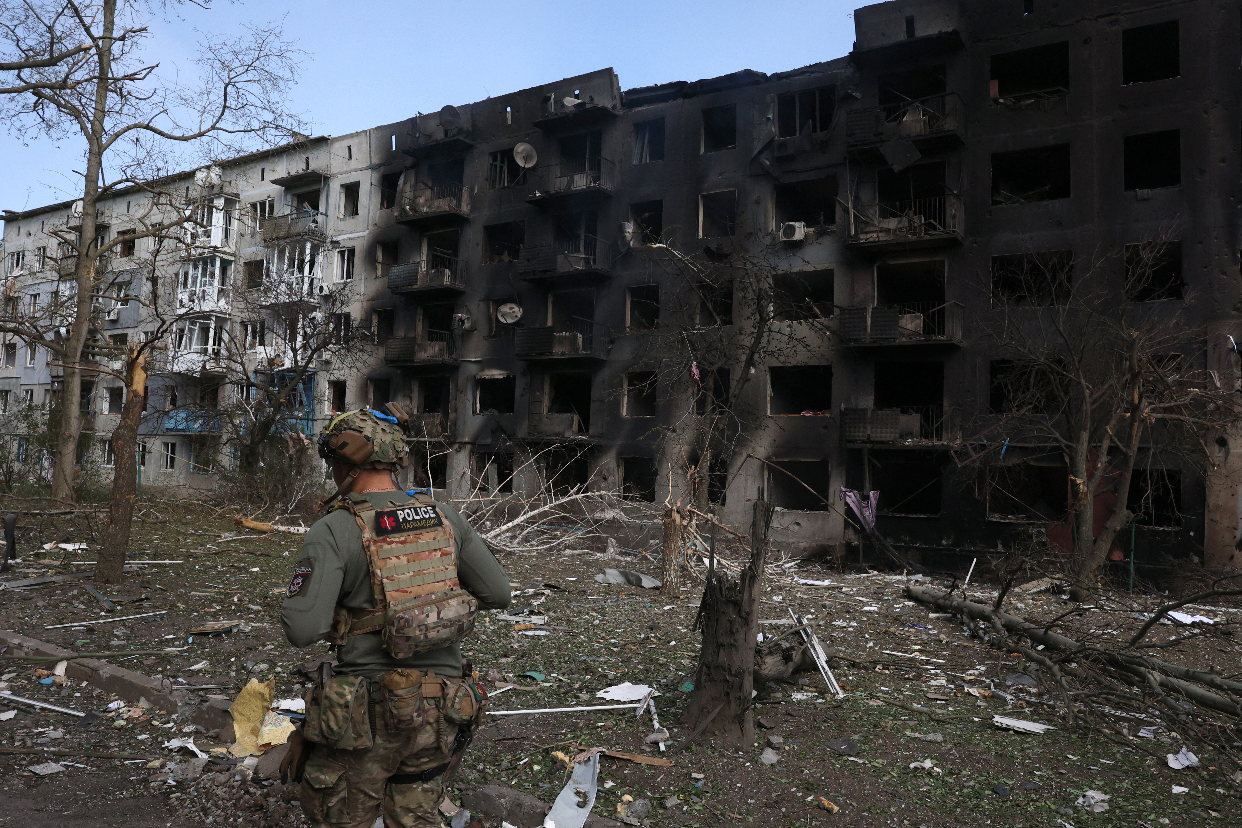 A Ukrainian police officer walks past a destroyed building near the wasteland of Avdiivka