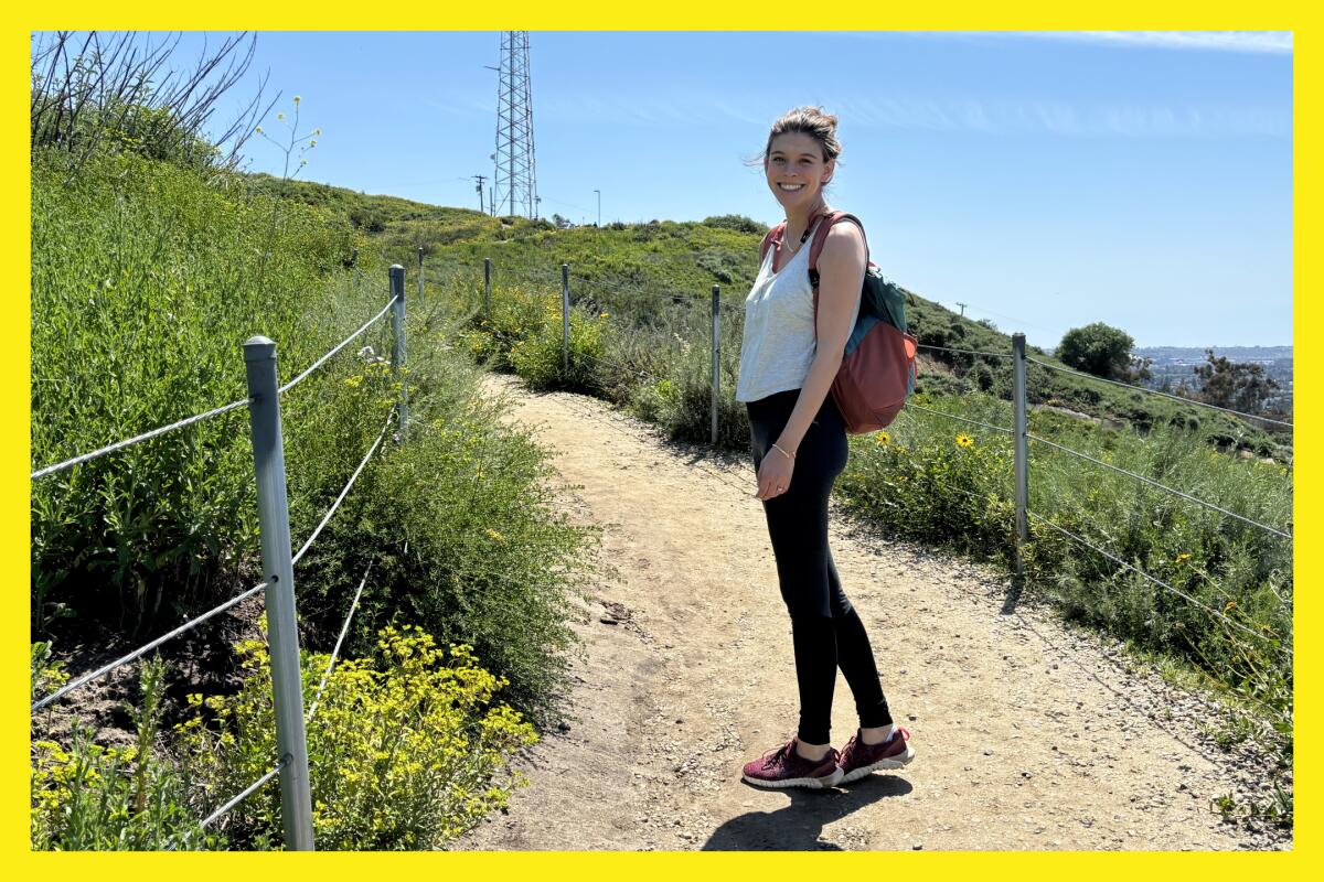 A woman poses for a photo as she is hiking a trail