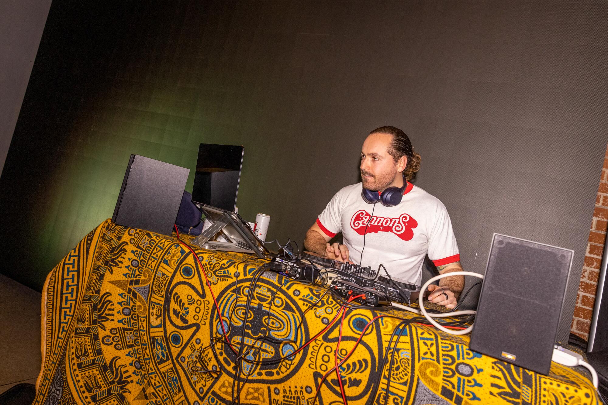 A man sitting behind a table DJing music.