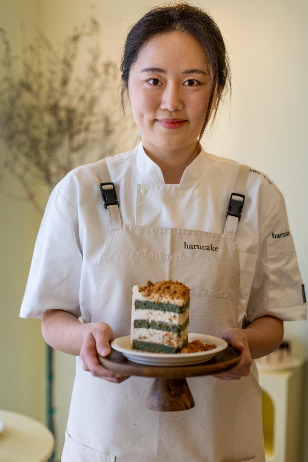 Ellie You, owner of Harucake, holds a slice of mugwort injeolmi cake.