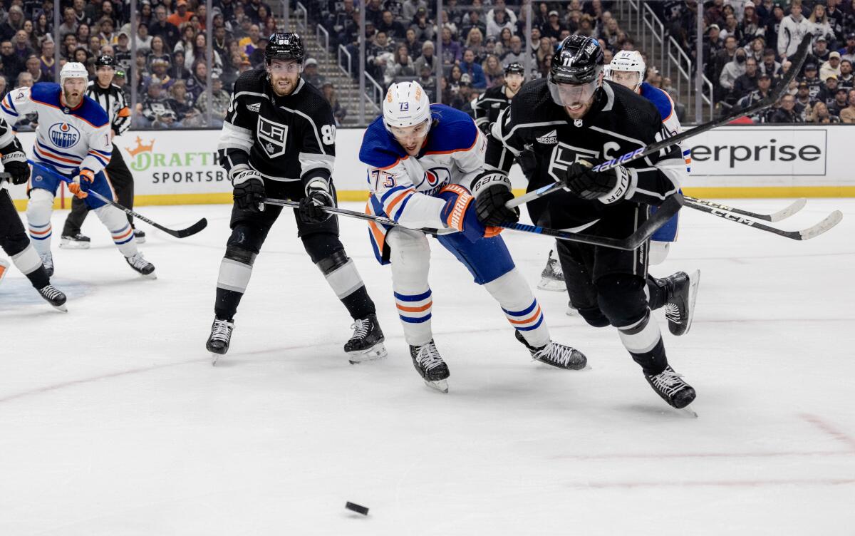 Kings center Anze Kopitar, right, battles Oilers defenseman Vincent Desharnais as he skates toward a loose puck.