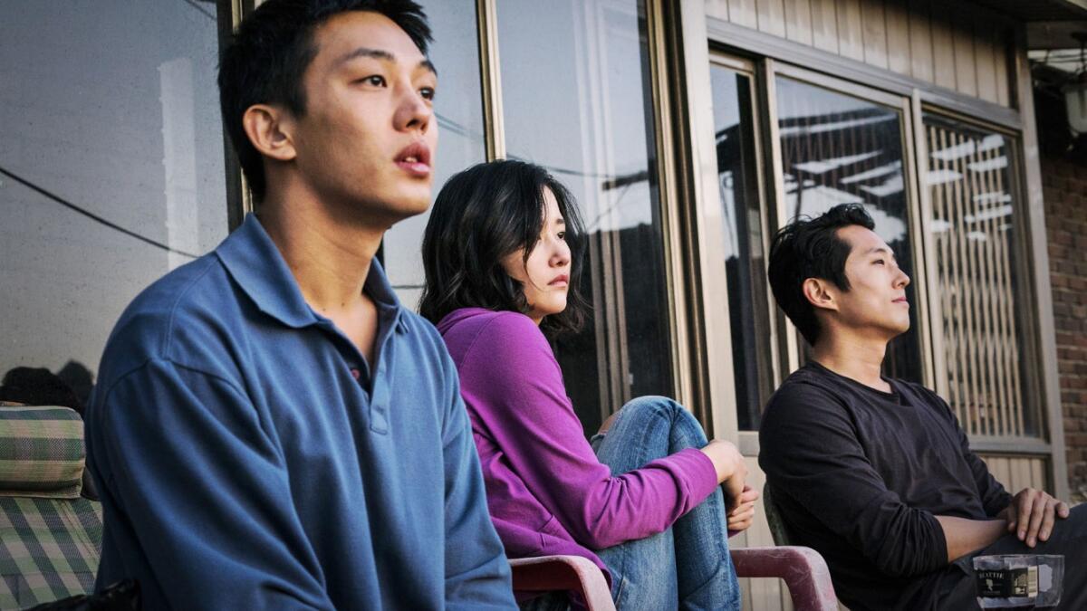 Two men and a woman sit on a porch.