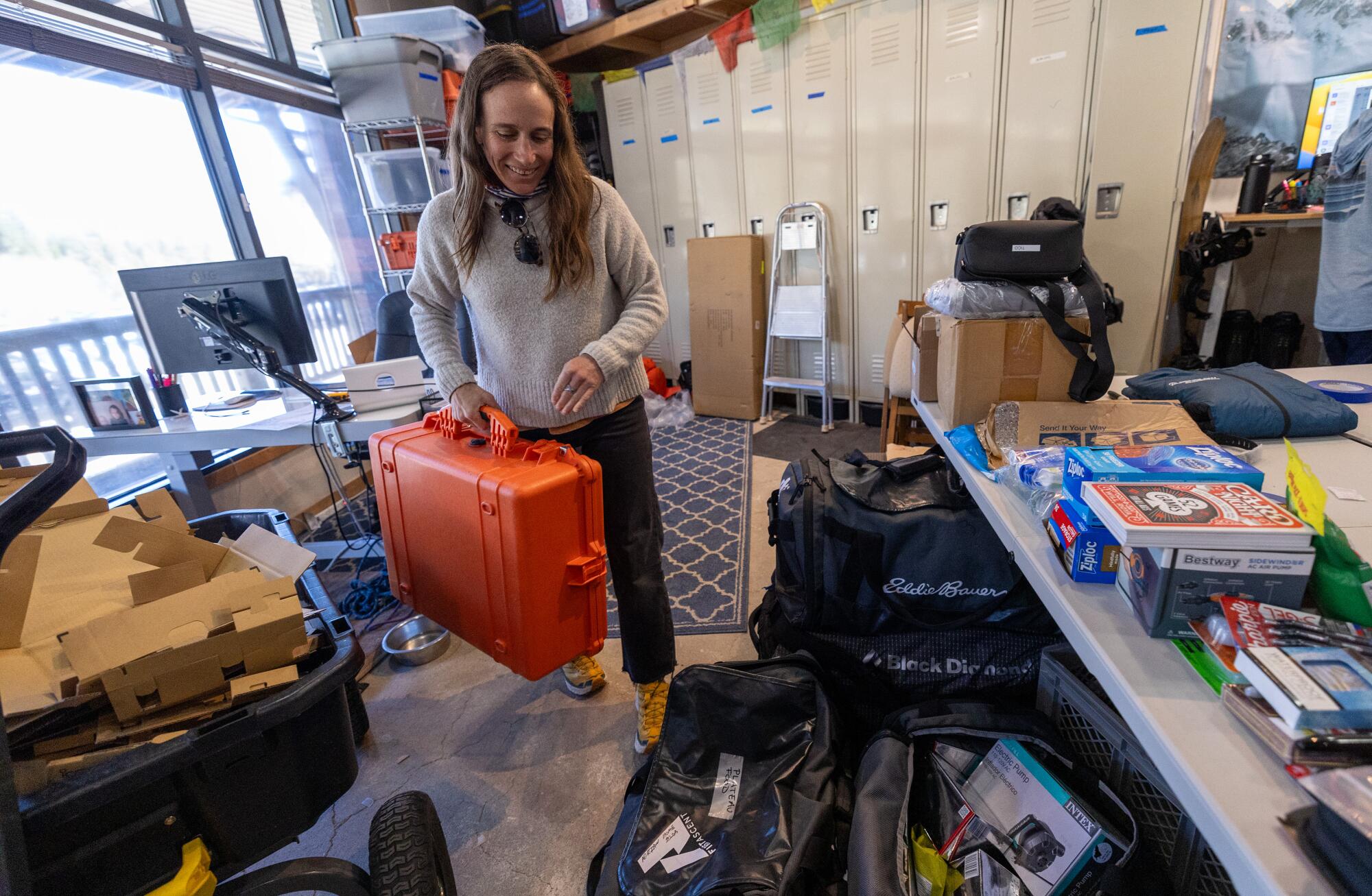 A woman in a sweater organizes luggage for a trip.