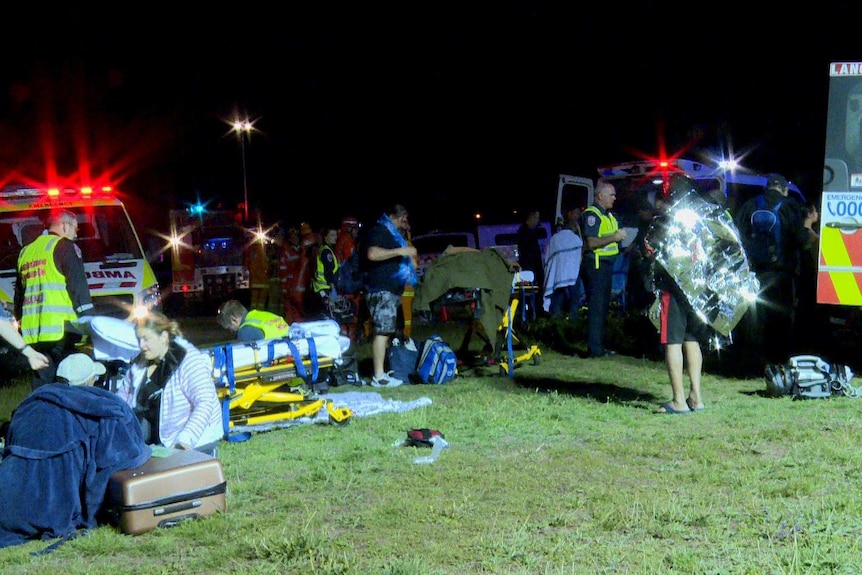 Paramedics assess men and women at night.