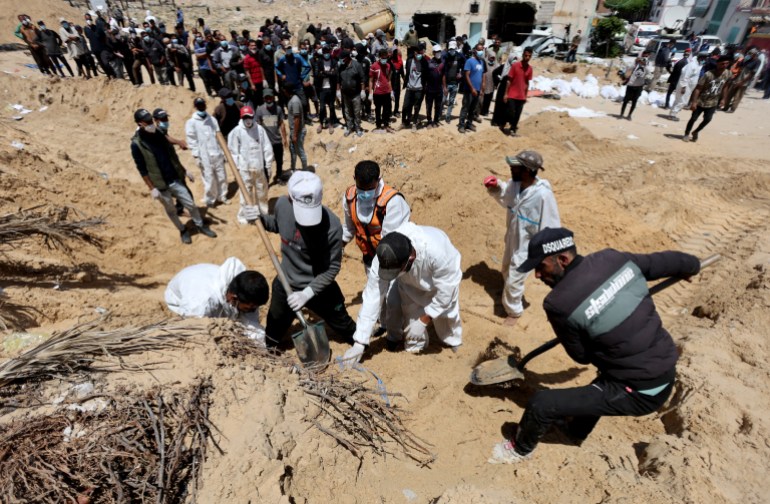 People work to move into a cemetery bodies of Palestinians killed during Israel's military offensive and buried at Nasser hospital