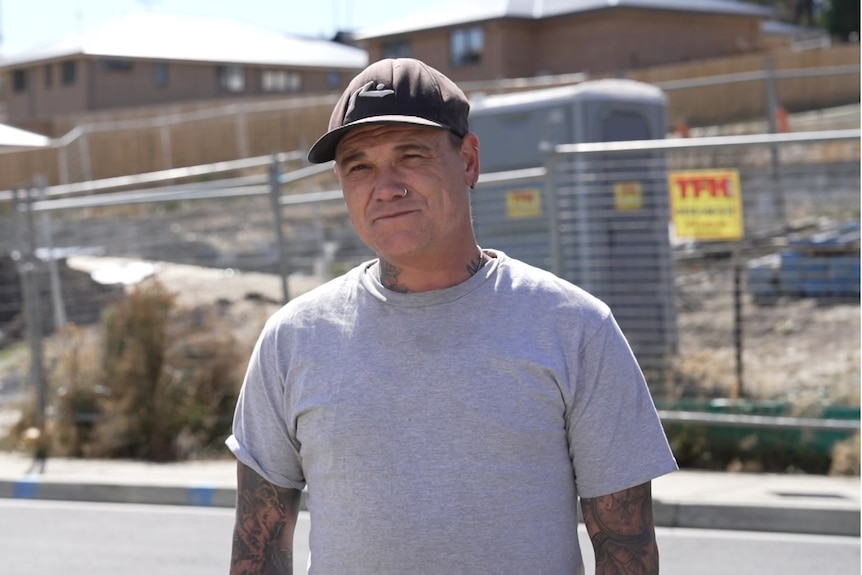 A man stands in front of a construction site