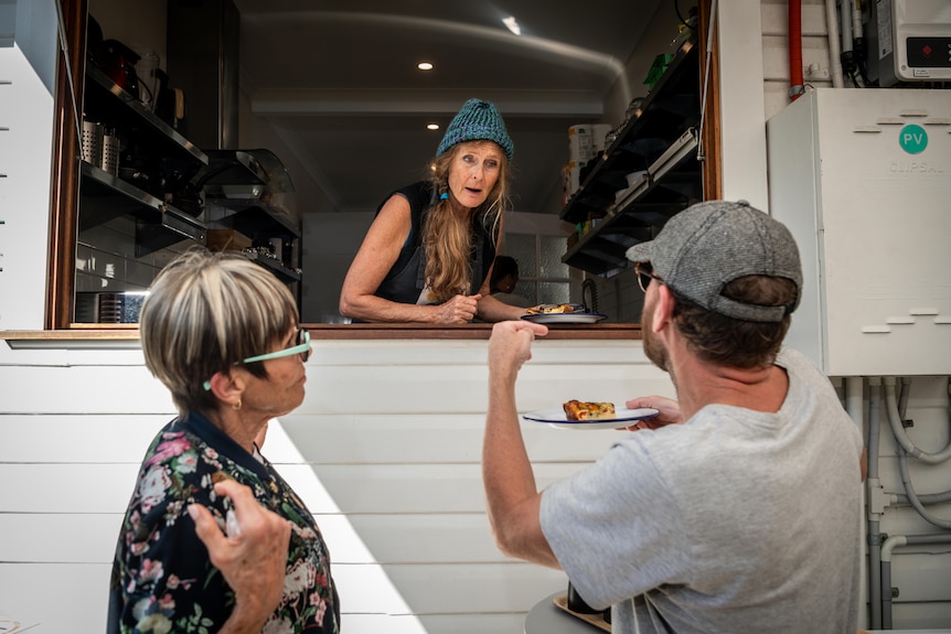 A man takes a plate of food from a woman at a high counter.