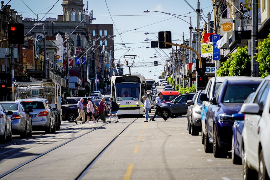 A main street in Camberwell showing pedestrians, cars and a tram.