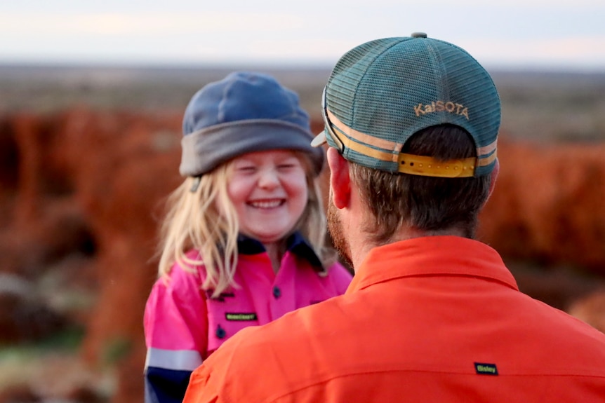 A blonde girl smiles at her dad.