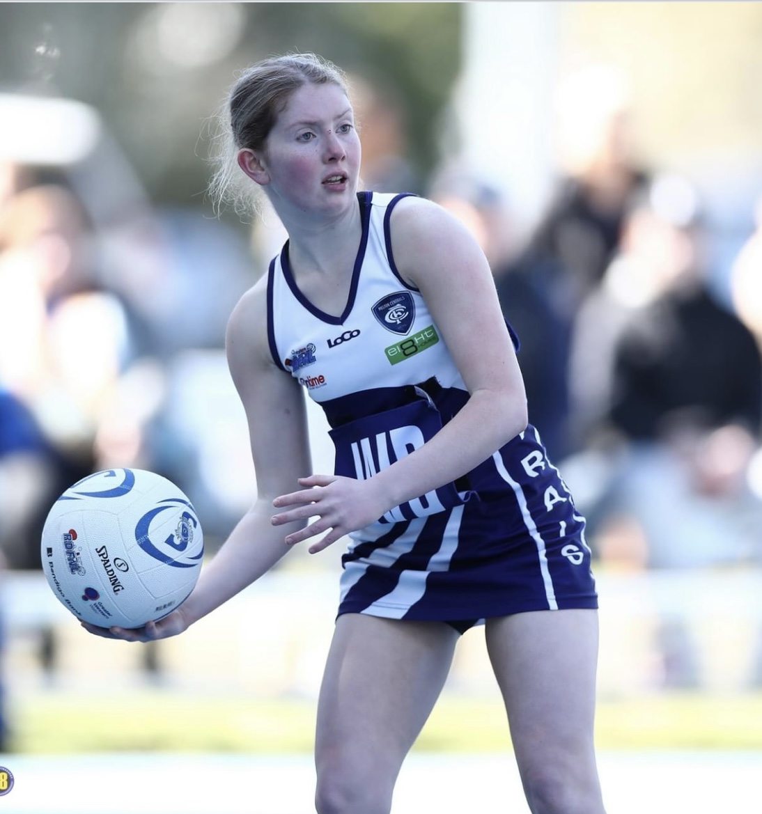 Mackenzie holding a netball on a court. 