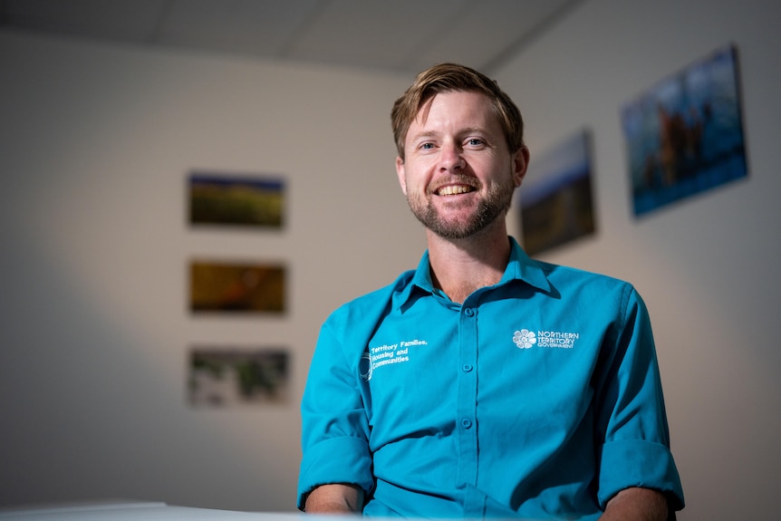 Brenden Boyce looks at the camera standing inside a room in a blue shirt.