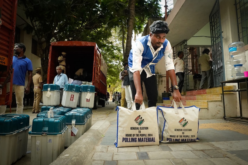 A man holding big bags with "polling material" written on it 