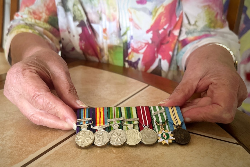 A woman's hands holding seven war medals