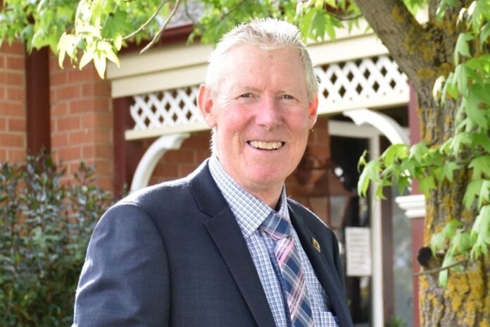 A man in a suit smiling outside a house