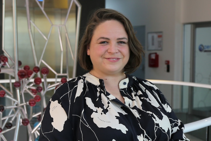 Sarah Hellewell standing in a research room smiling.