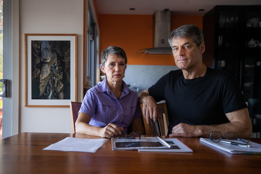 Man and woman sitting at a dining table with documents in front of them.