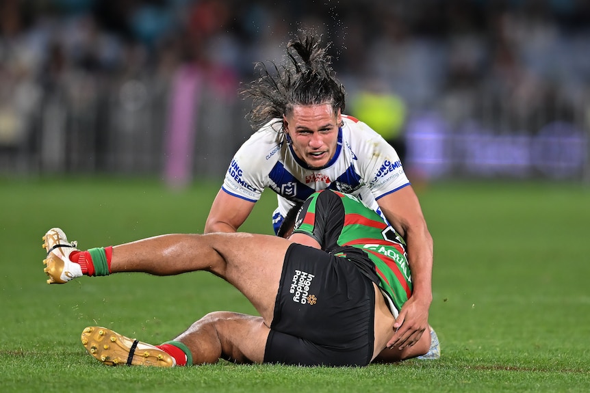 NRL player Jackson Topine, lying on top of an opponent after tackling them