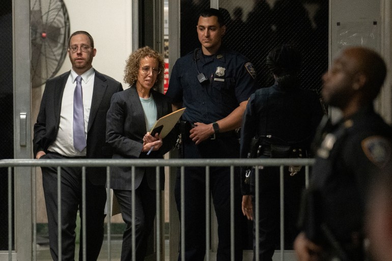 Susan Necheles walks out of the courthouse, which is barricaded by a temporary metal fence.