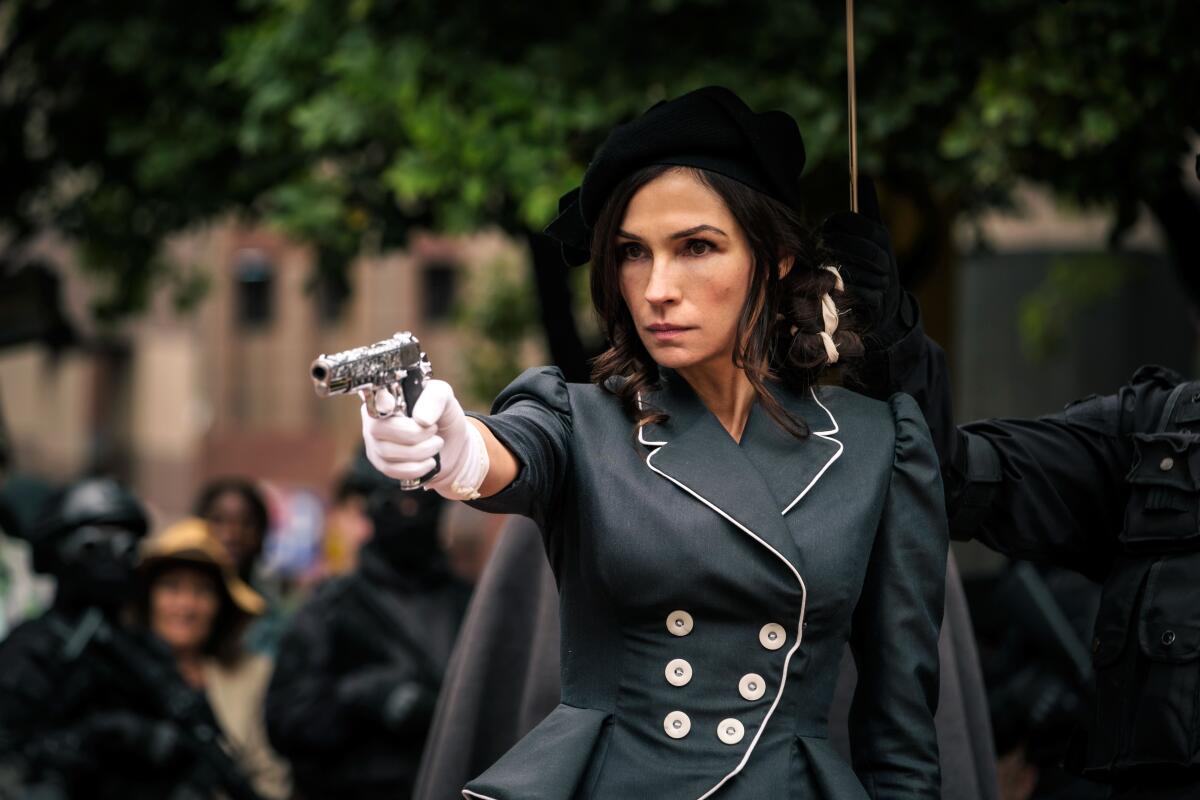 A woman points a pistol.