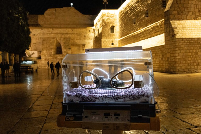 a bronze statue inside an illuminated incubator outside a stone church