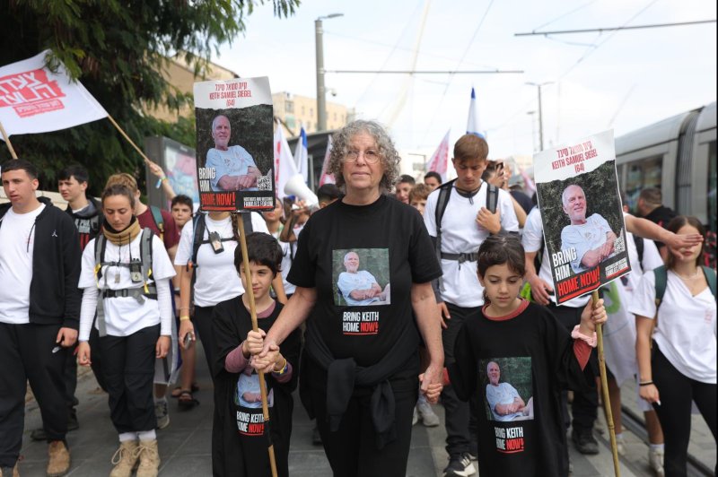 Aviva Siegel, center, holds a picture of her husband Keith Siegel as she marches with her grandchildren and other Israelis calling for the return of hostages held in Gaza. Hamas on Saturday released a video showing Siegel and another hostage, Omri Miran, apparently in good health. Photo by Abir Sultan/EPA-EFE