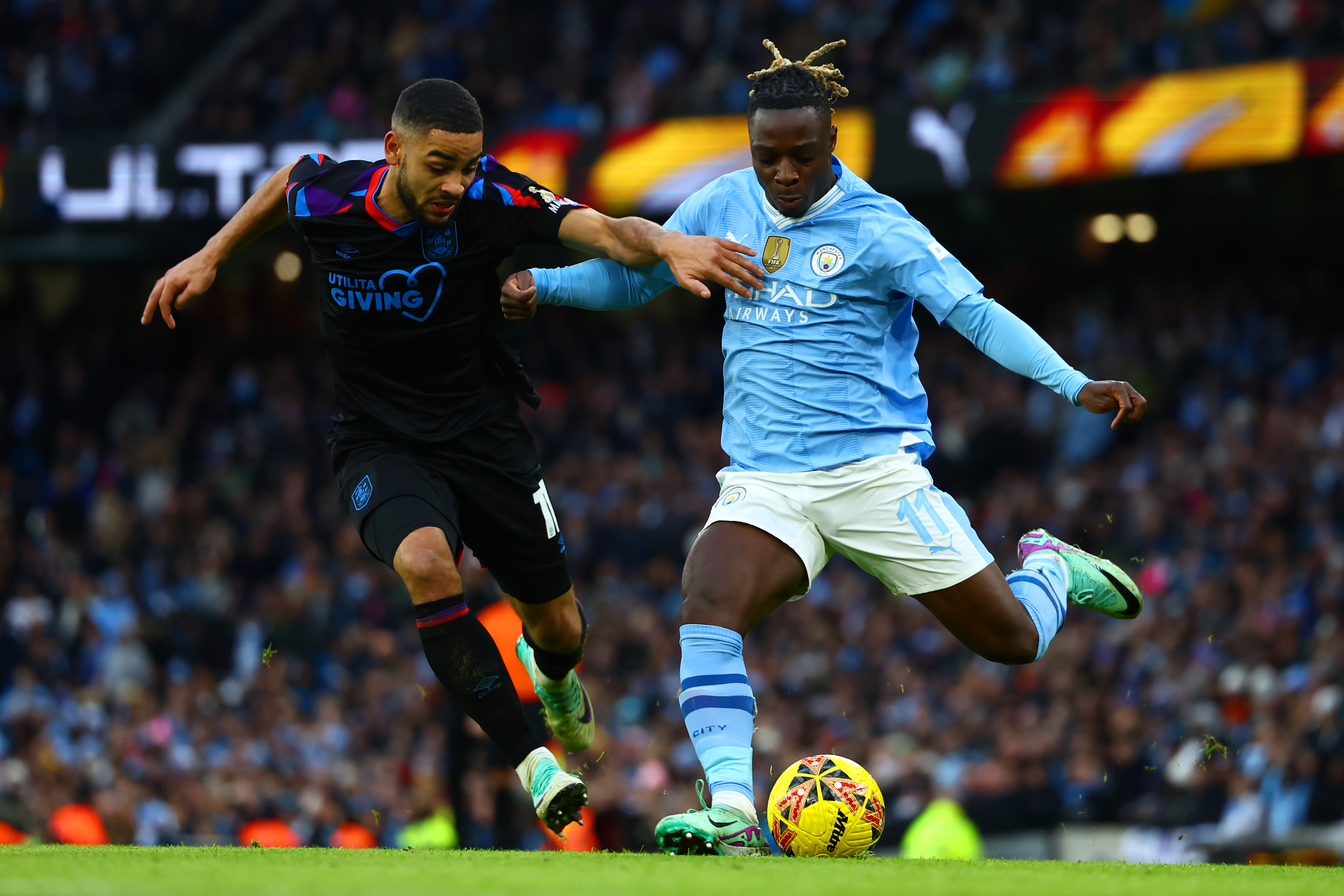 Brodie Spencer tries to tackle Manchester City's Jeremy Doku at the Etihad