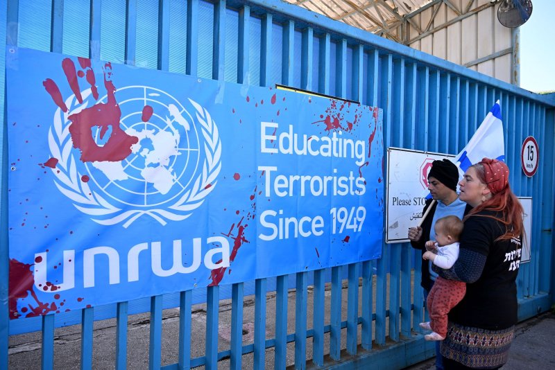 Israeli right-wing protesters look at a banner hung on the entrance to the United Nations Relief and Works Agency for Palestine Refugees, headquarters in Jerusalem on March 20. Japan said it will start funding the agency again on Tuesday. Photo by Debbie Hill/UPI