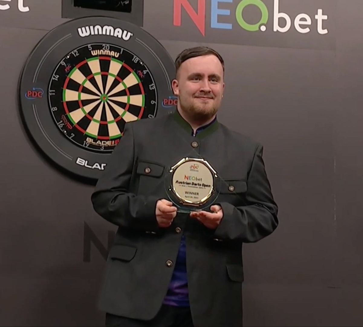 Luke Littler shows off the green jacket and trophy he won for the Austrian Darts Open