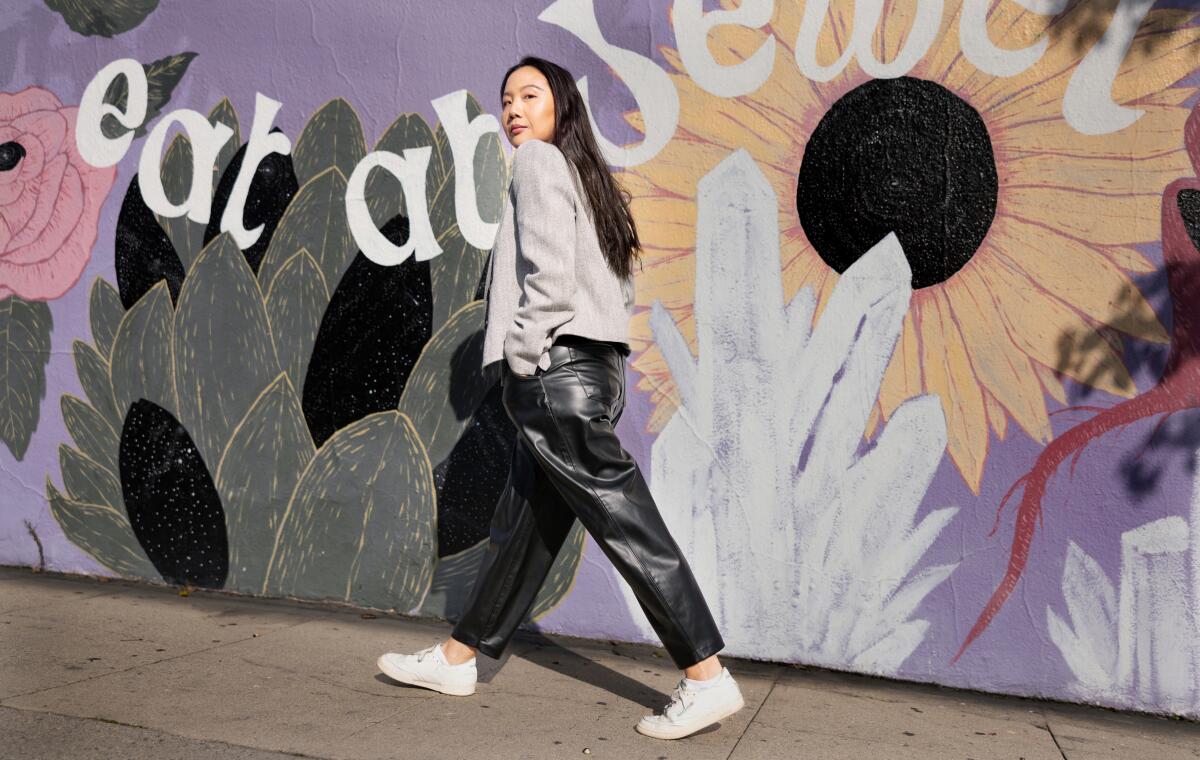 Woman in a business suit walking and looking back in front of a cafe mural