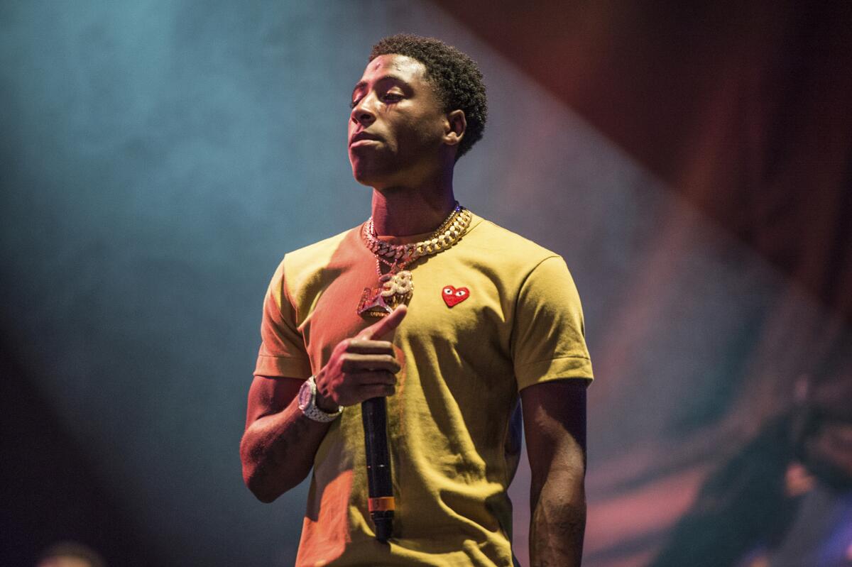 A man in a yellow shirt holding a microphone on a stage