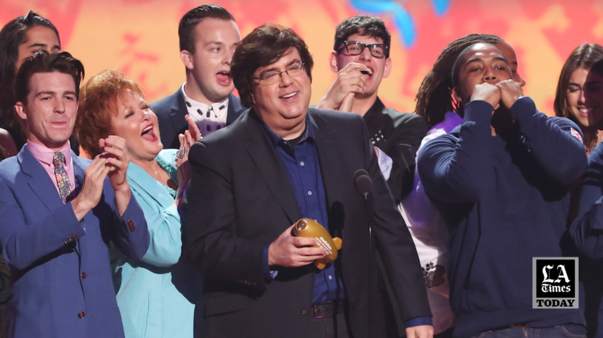 A man accepts an award as people around him applaud