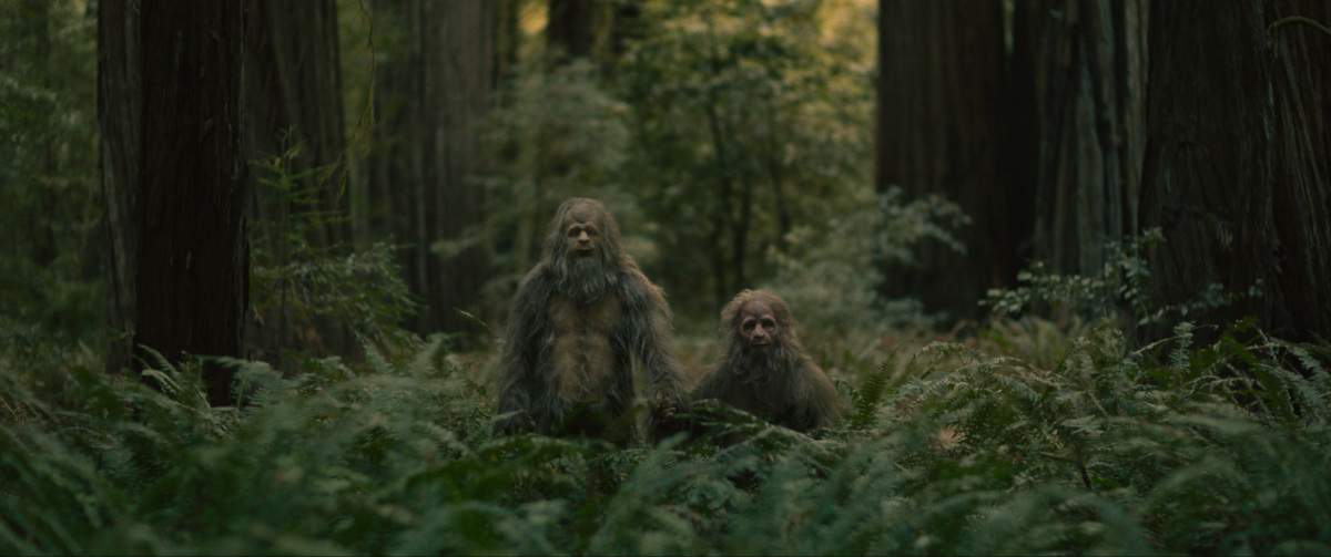 Two actors wear Sasquatch costumes in the woods.